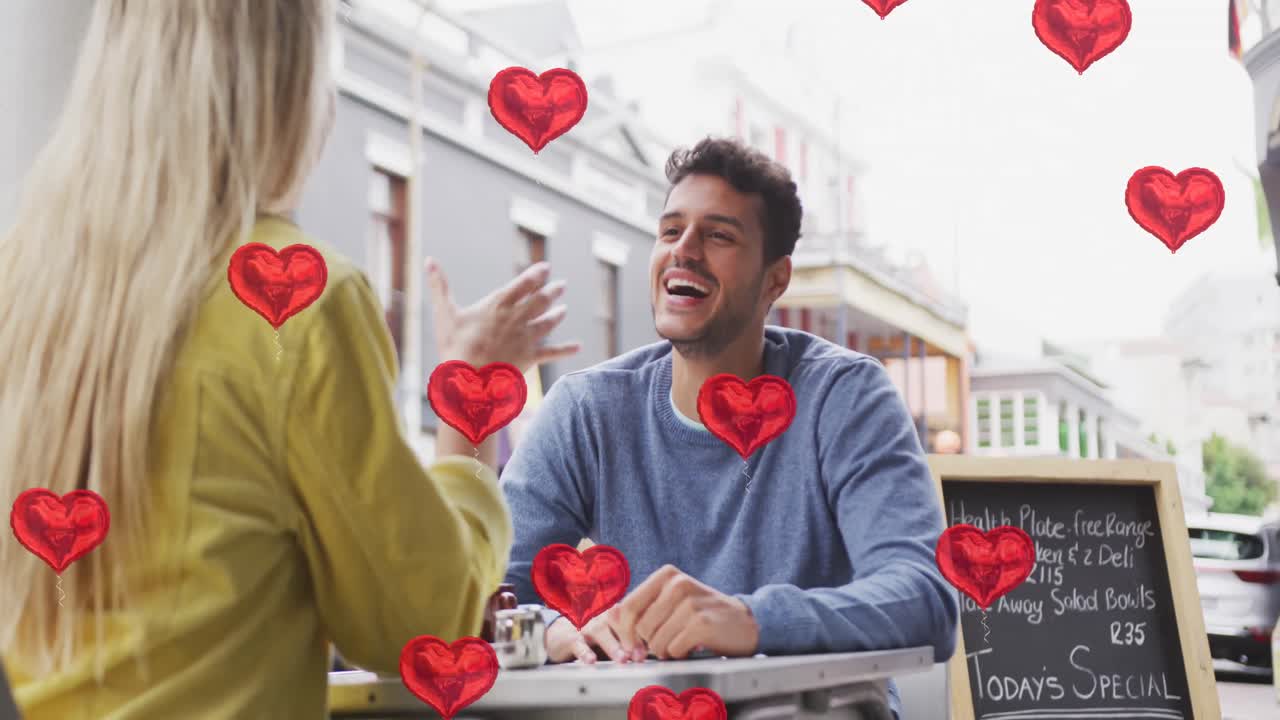 animación de iconos de corazón flotando sobre una feliz pareja caucásica hablando y sonriendo