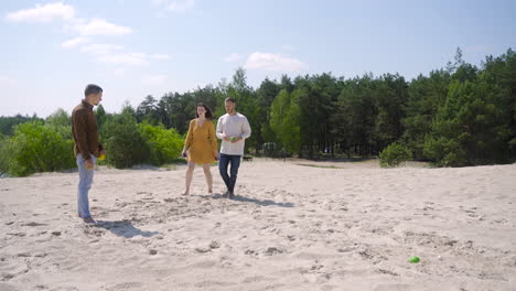 group of caucasian friends playing petanque on the beach on a sunny day