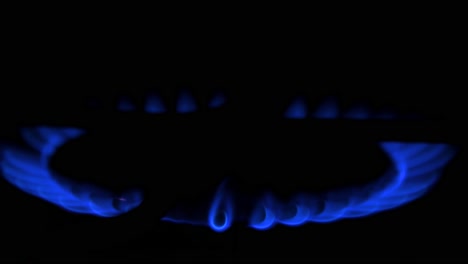 Gas-burning-from-a-kitchen-gas-stove,-dark-background,-cold-winter-and-energy-crisis-concept,-closeup-shot