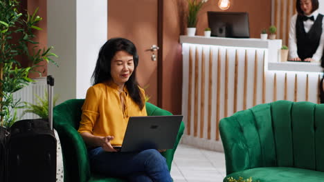 Asiatische-Frau-Erhält-Kaffee,-Während-Sie-Am-Laptop-Arbeitet