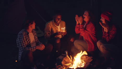 friends celebrating birthday by campfire