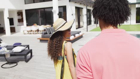 video of happy diverse couple arriving with suitcase at sunny holiday resort