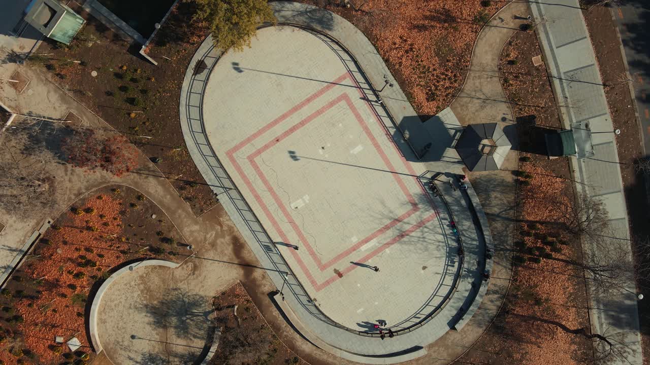 antena de arriba hacia abajo girando sobre la gente disfrutando en la pista de patinaje en el parque otoñal en los dominicos, santiago, chile