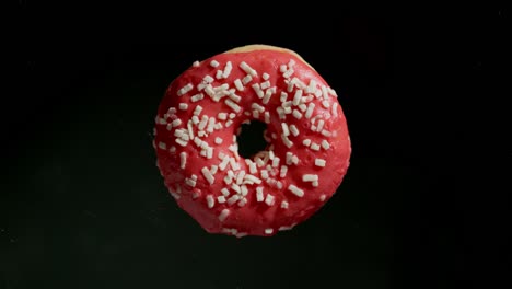 aplastando una rosquilla rosa sobre un fondo negro