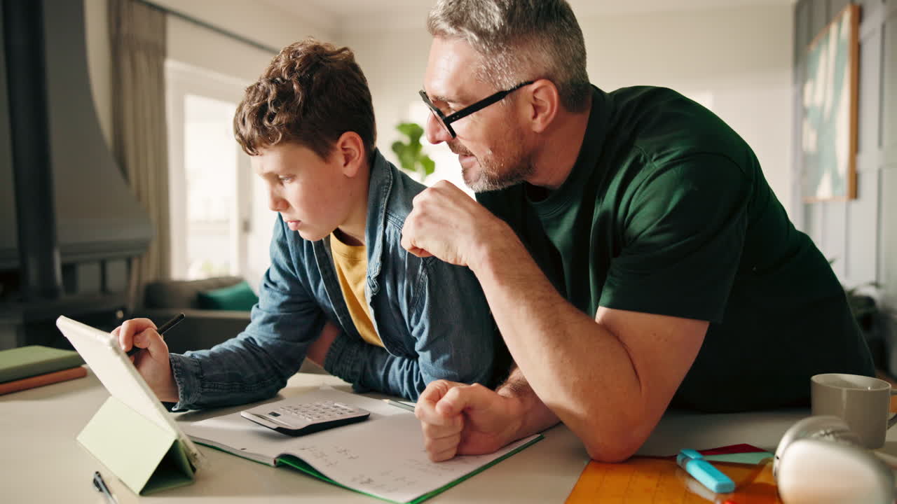 Father helping son with homework using tablet