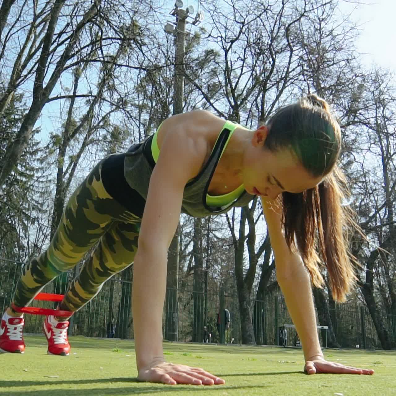 Young sporty woman runner with elastic bands outside at the stadium. Beautiful girl doing exercises. Healthy sports lifestyle