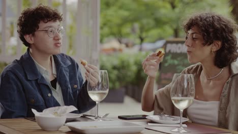 two people enjoying a meal and drinks at an outdoor restaurant