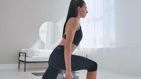 a woman at home on a sunny day in the living room lunges back with dumbbells in her hands. healthy lifestyle daily exercise at home.