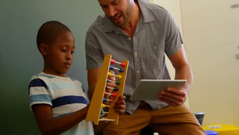 Front-view-of-young-Caucasian-male-teacher-teaching-schoolboy-to-use-abacus-in-classroom-4k