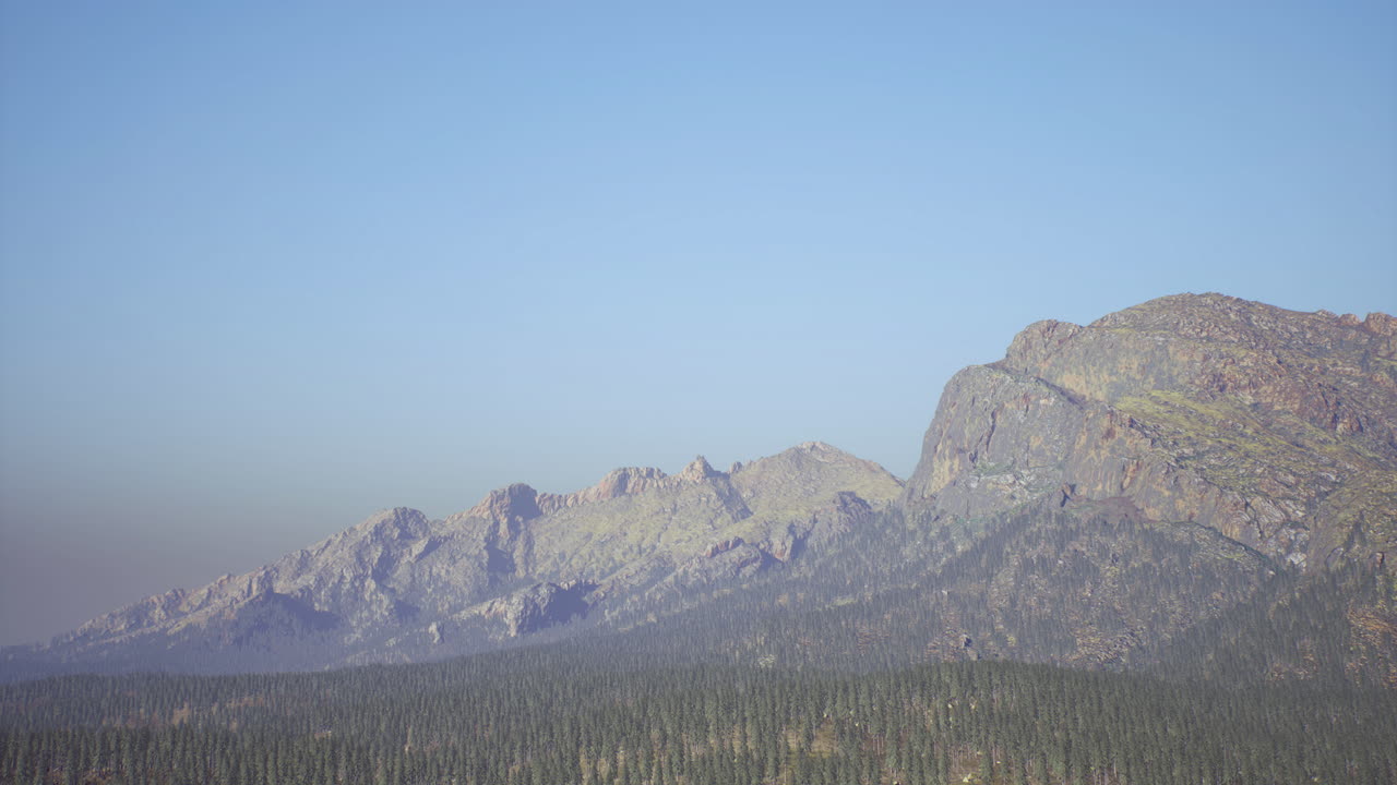 은 파란 하늘 아래의 웅장한 산맥과 그 아래의 상록 숲