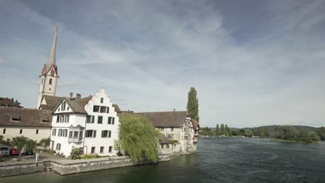 switzerland town on river banks with bell tower in background