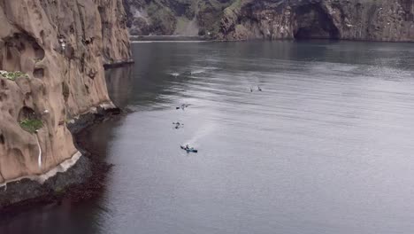 grupo de aventureros en kayaks explorando altos acantilados de la isla heimaey, antena