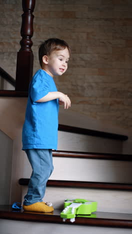 cute baby boy carefully steps on the stair where sunglasses lie and a guitar. kid stands waving his hands. vertical video.