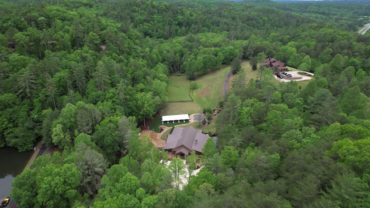 Scenic zoom out from a house nestled in lush green forest, showing vast natural surroundings.