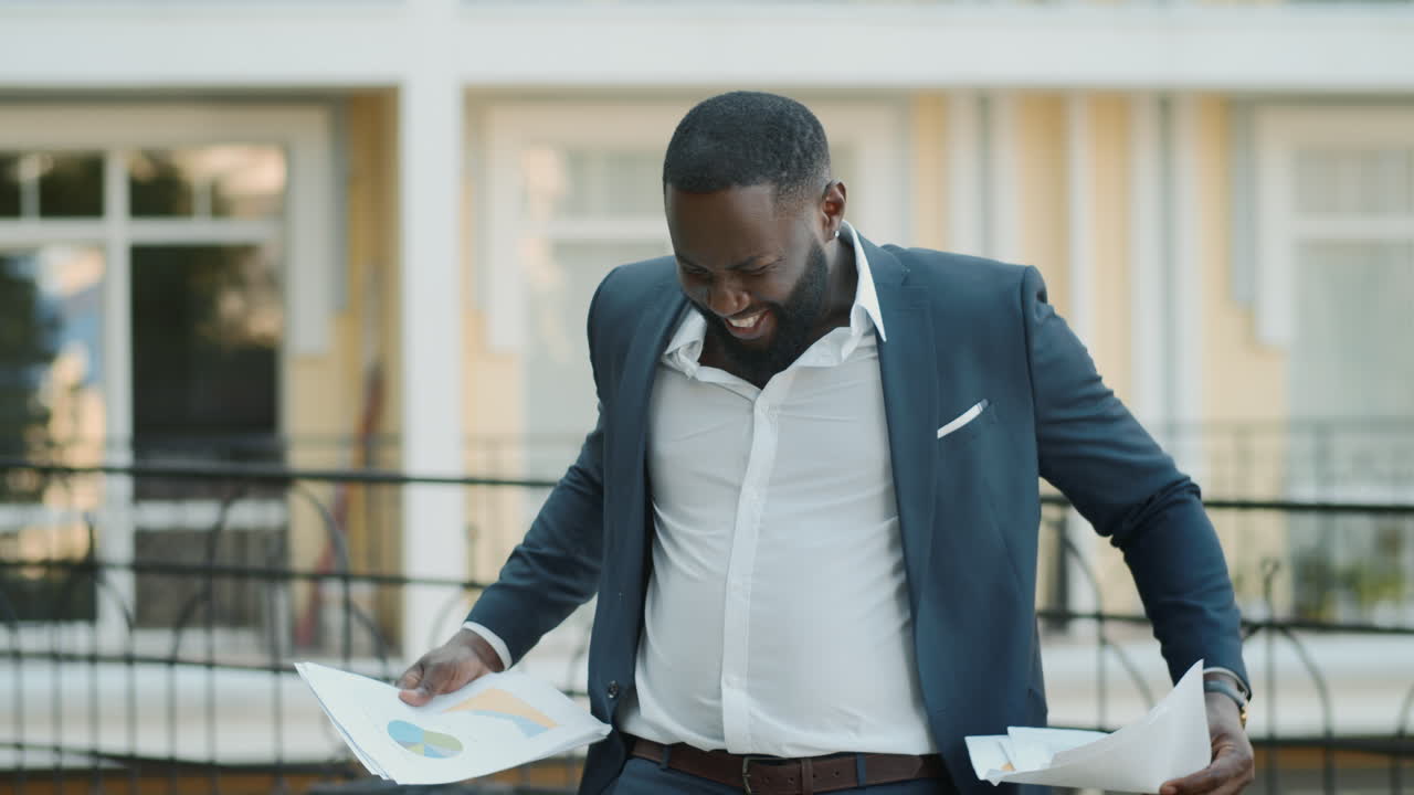 Homme d'affaires heureux examinant des documents en extérieur. Homme afro debout dehors.
