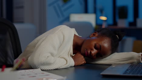 dark skin freelancer working overtime falling asleep with hand on desk