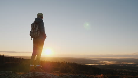 a woman traveler stands on top of a mountain looks at the beautiful landscape ahead admires the natu