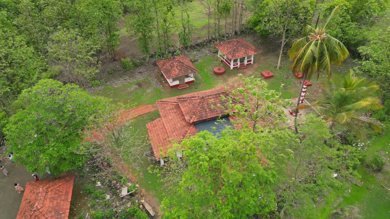 A stunning drone shot of Avalegaon Temple in Kudal, Konkan, Maharashtra, nestled amidst lush green trees. The temple stands as a serene spiritual retreat with the surrounding natural beauty