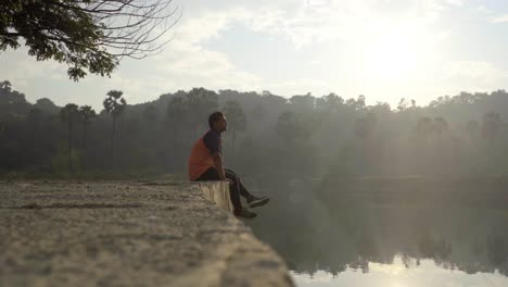 Junge-Sitzgelegenheiten-Auf-Einem-Dock-Am-See-Besorgt-Intensiv-Traurig-Genießen-Blick-In-Sonnenaufgang-Morgen-Junge-Mann-Wasser-See-Reavilling-Schuss-Spiegelung-Im-Wasser