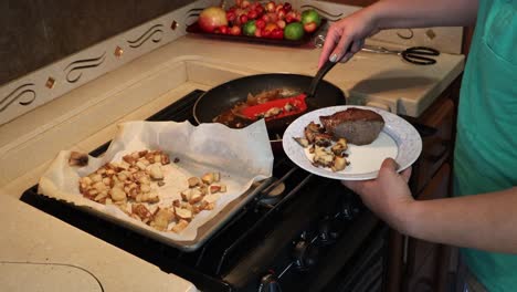 woman plating steak, grilled onions, sauteed miatake mushrooms and roasted potatoes in a tiny home kitchen