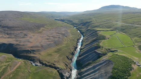 Overhead-view-birds-eye-of-Jokulsa-river-flowing-in-Studlagil-Canyon,-Vatnajokull-national-park.-Top-down-view-of-glacier-river-streaming-through-basalt-rock-columns-formations