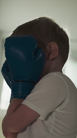 kid learns to do block with instructor in combat gym. combat master trains preschooler boy to protect head during boxing in sports club slow motion