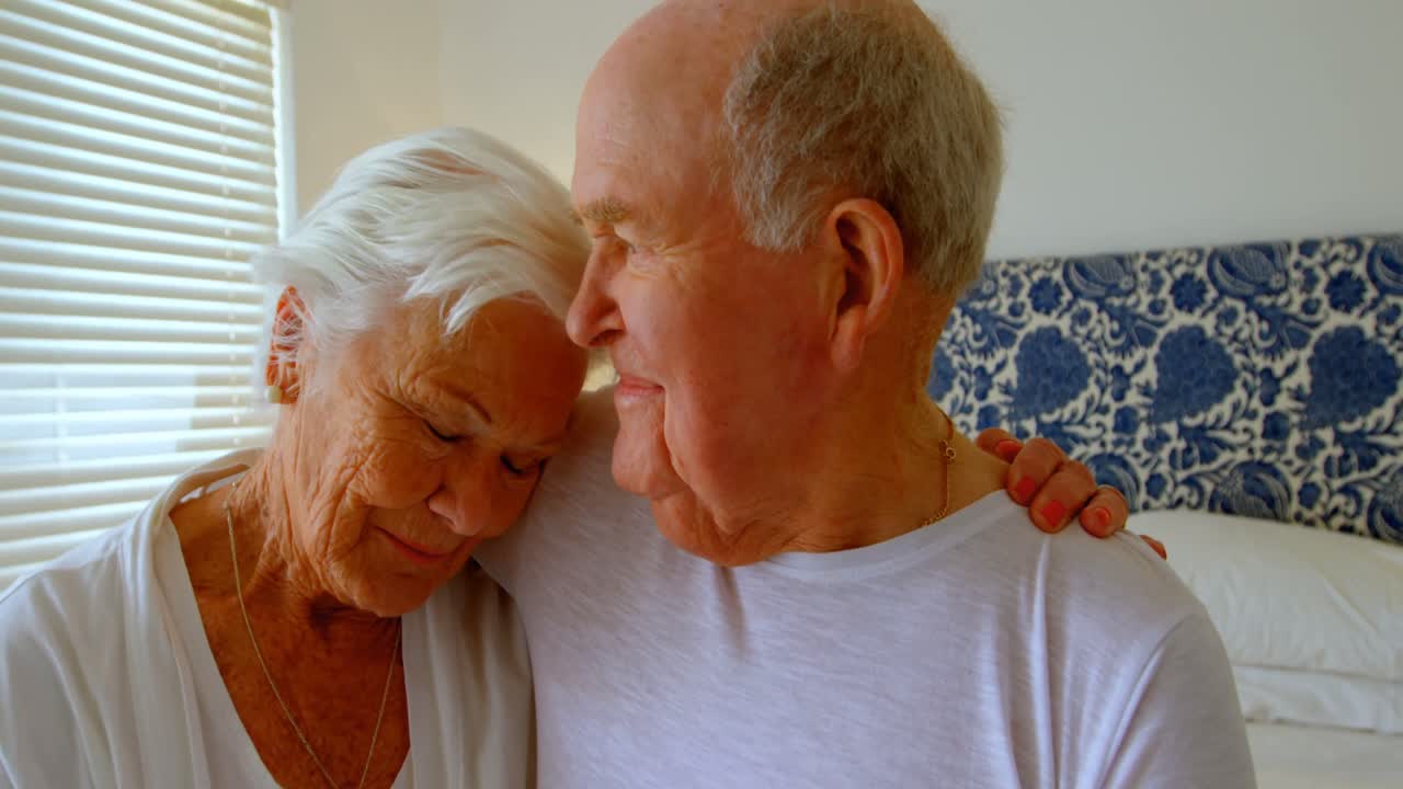 편안한 집 4k의 침실에서 서로 포옹하는 백인 노인 커플의 앞면
