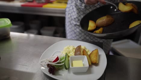 Chef-Plating-Freshly-Cooked-Potatoes-In-The-Kitchen---dolly-shot,-slow-motion