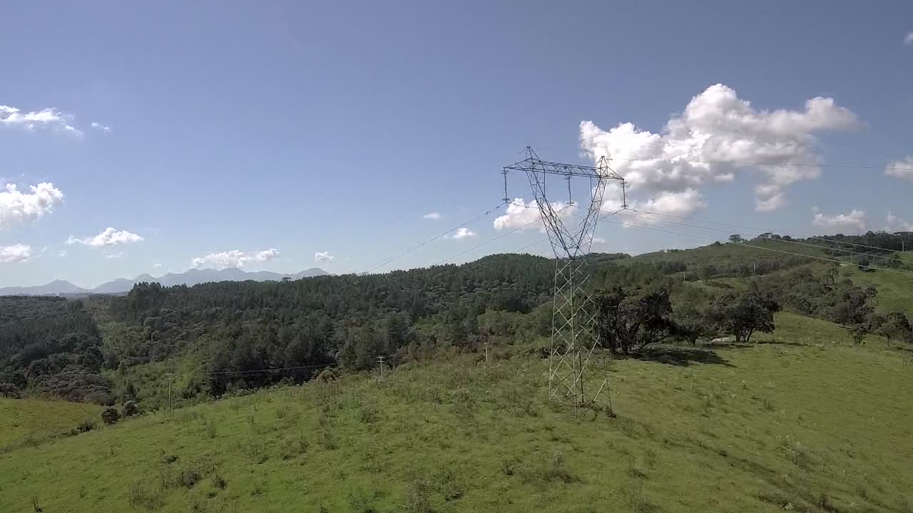 A transmission tower, as known as a power tower, laying on a big green carpet on a sunny day with blue sky, providing clean energy for a good part of a city