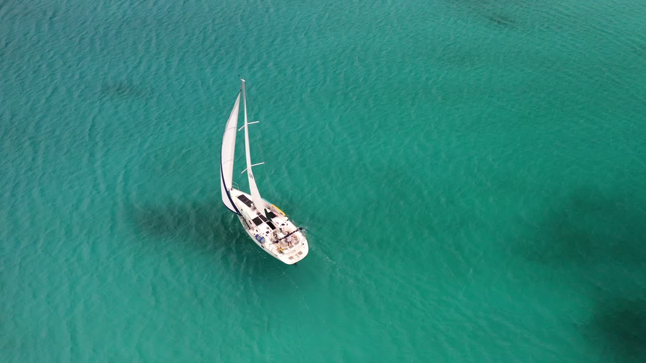 White Sailboat Cruising In The Ocean With Clear Blue Water In The Bahamas. - aerial
