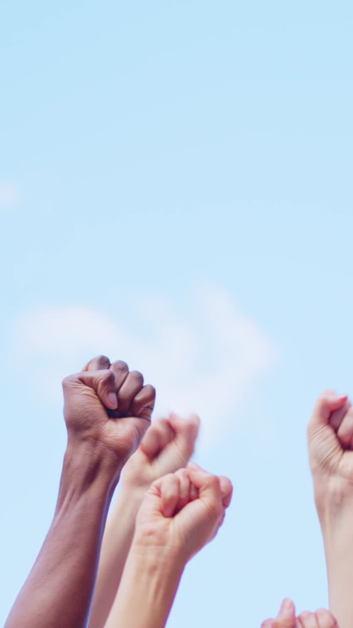 Diverse Fists Raised in Protest and Unity Against a Blue Sky