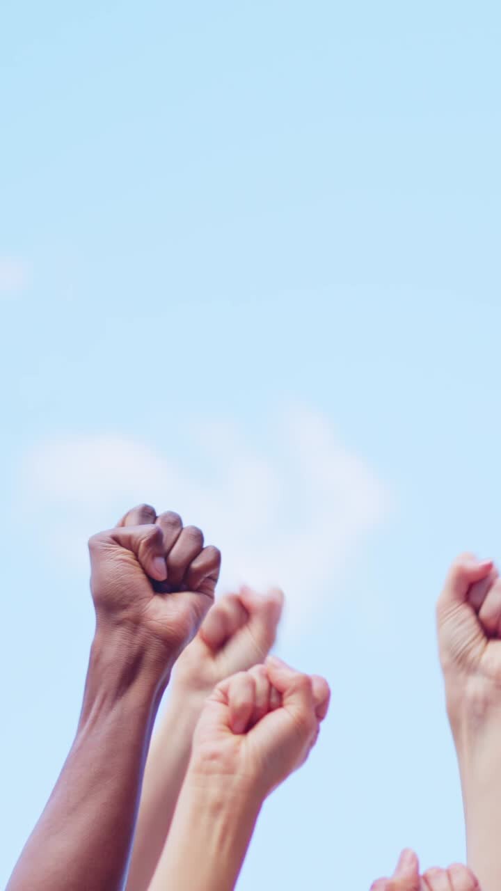 Diverse Fists Raised in Protest and Unity Against a Blue Sky