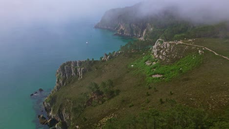 vertically tilted up drone movement near foggy cliffs virgin island beach coast with calm turquoise sea, crozon peninsula, brittany, france