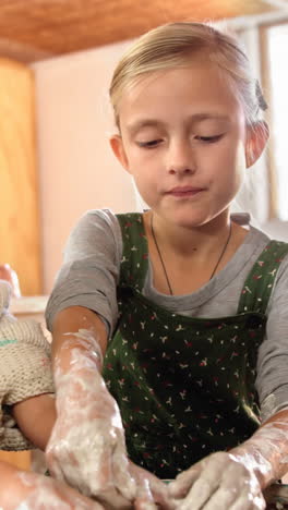 girl assisting her sister while making a pot