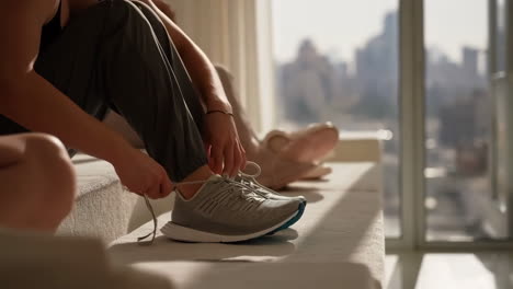 person tying shoelaces in an apartment with a city view