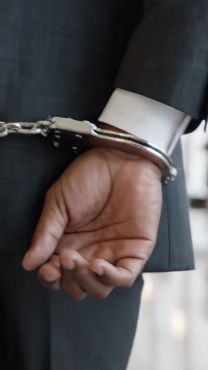 A Close-Up View of a Handcuffed Individual Highlighting the Contrast Between Formally Dressed Attire and the Constraints Imposed by Handcuffs