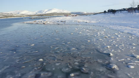 an icy shorline along a snow covered island in the arctic circle, aerial forward movement