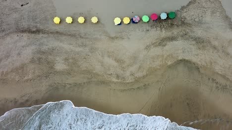 white sand coast sea shore aerial drone flying above colorful umbrellas beach