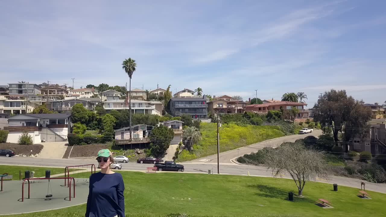 핫팬츠와 베이스 캡이 돌 위에 서 있는 코로나 전염병 빈 놀이터 여성