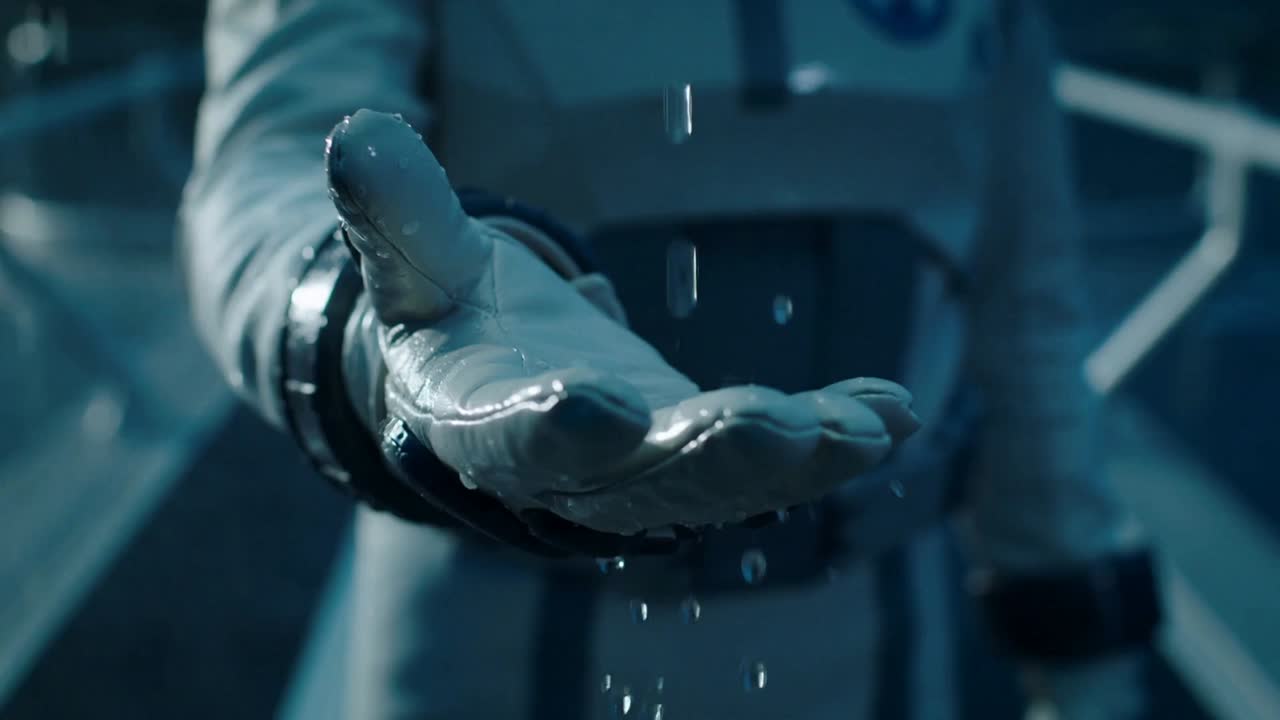 Extending suited pilot catching rain on gloved palm on platform, observing storm through lit visor