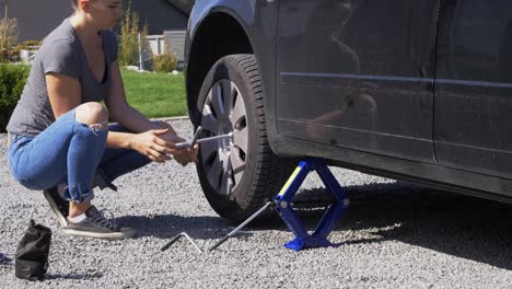 young female repairing damaged car tyre roadside vehicle breakdown