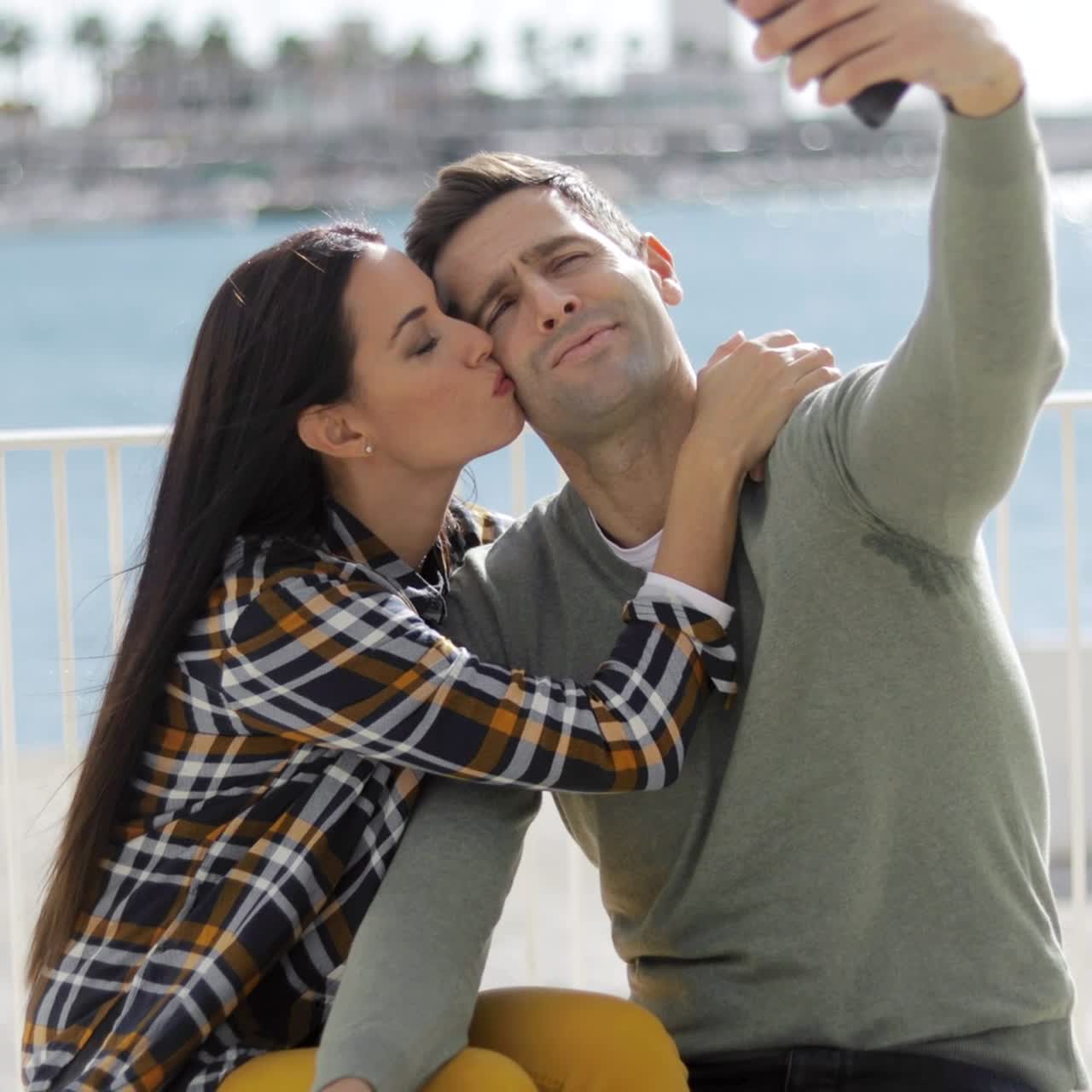 Pareja joven tomándose un selfie junto al mar