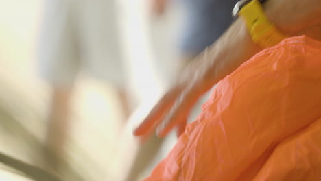 Close-up-of-a-person's-hands-folding-an-orange-parachute