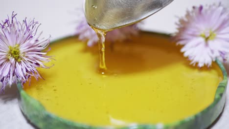 miel transparente se vierte de una cuchara en una tapa, un cuenco. primer plano. 4k