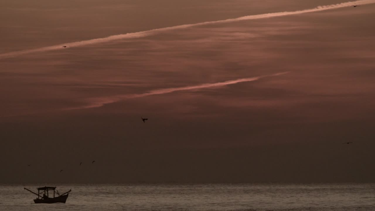 pequeño barco de pesca en el mar, cielo naranja después del atardecer, estático