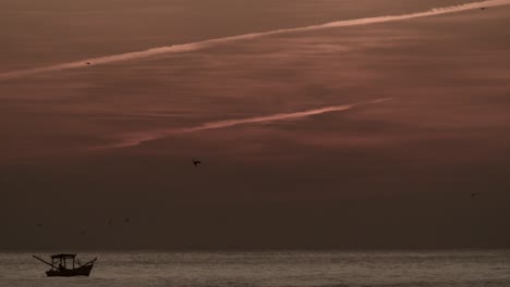 pequeño barco de pesca en el mar, cielo naranja después del atardecer, estático