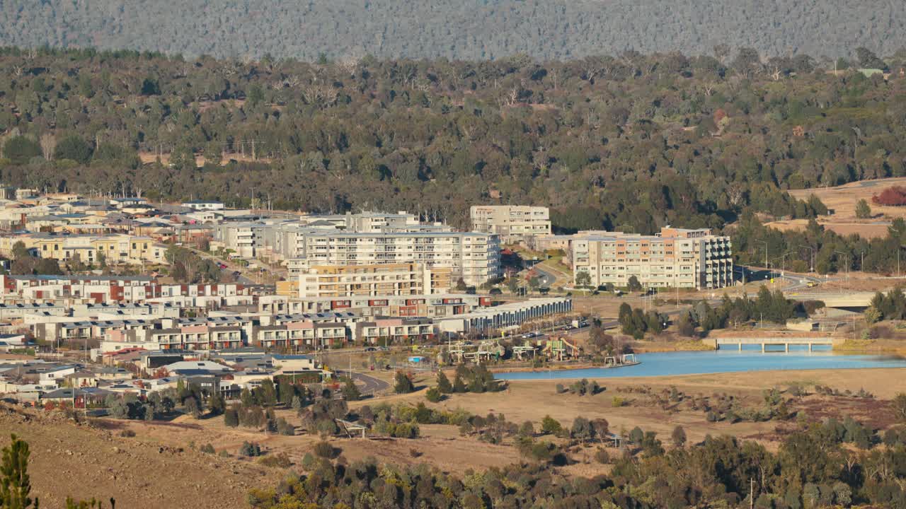 Morning traffic flows through a growing Canberra suburb with modern housing and apartments visible from above