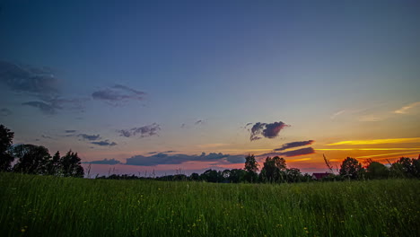 timelapse shot of beautiful sunset green grasslands in front of a cottage at dusk