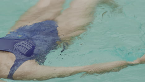 mujer irreconocible relajándose en el agua en la piscina