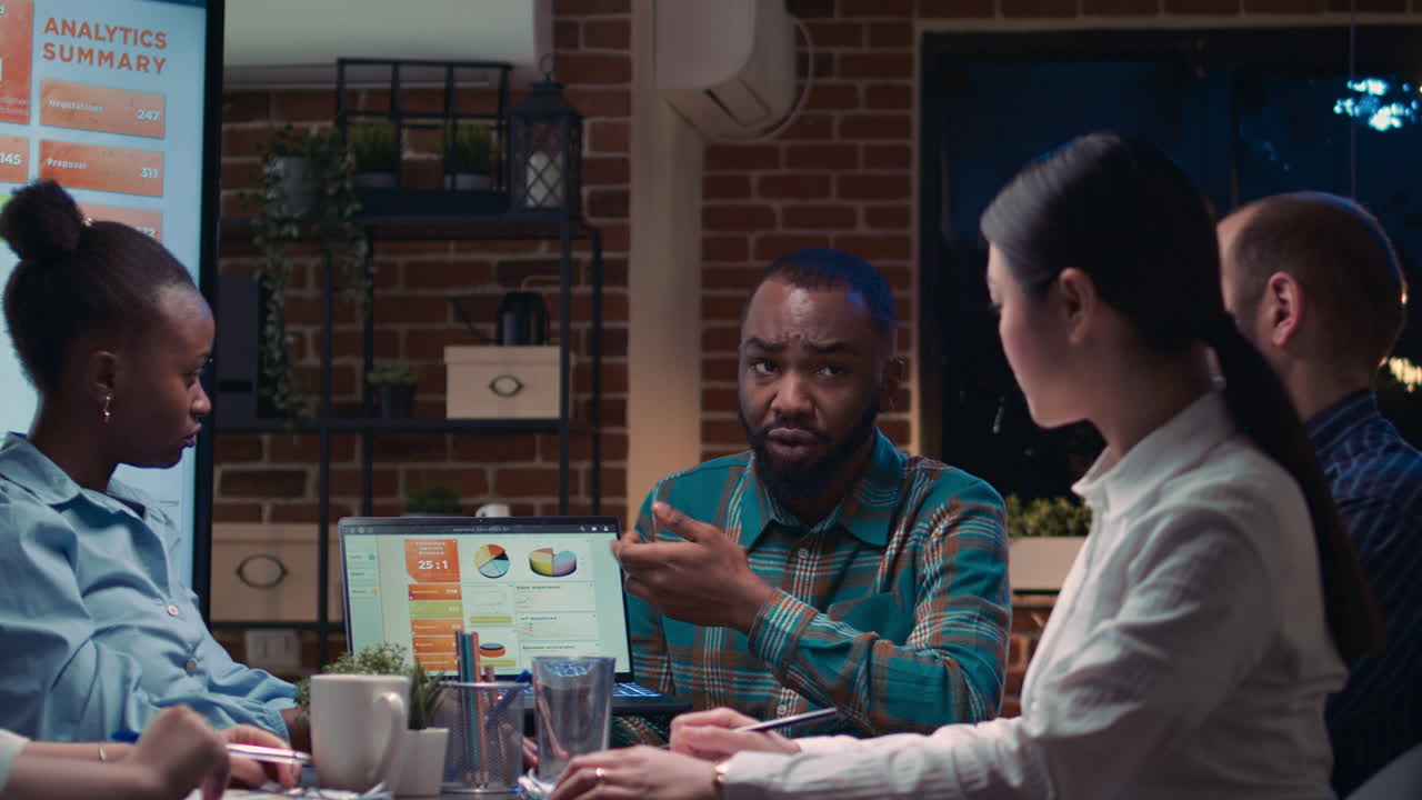 Coworkers brainstorming, analyst showing revenue statistics on laptop screen